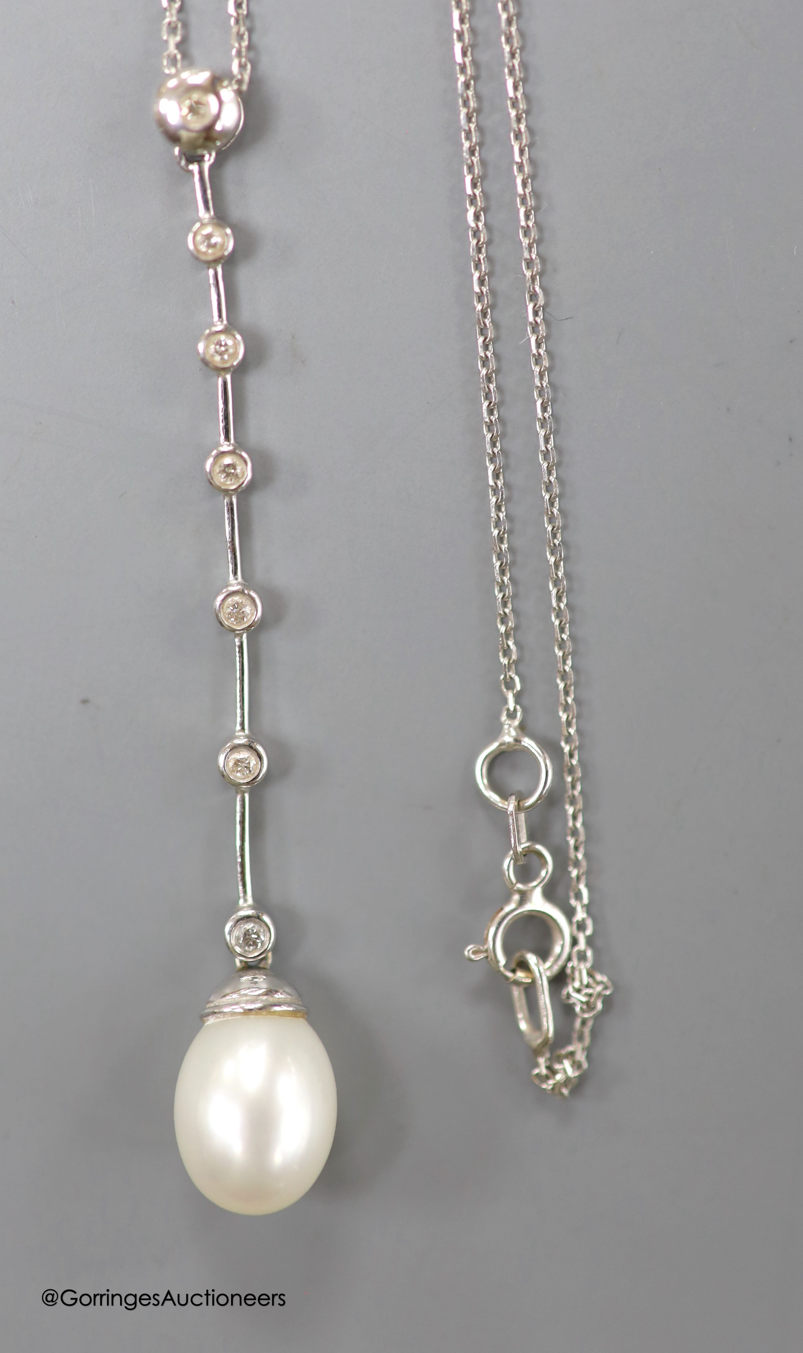 A modern white metal (stamped 14kt), cultured pearl and seven stone diamond chip set drop line pendant necklace, pendant 6cm, chain, 45cm, gross weight 4.1 grams.